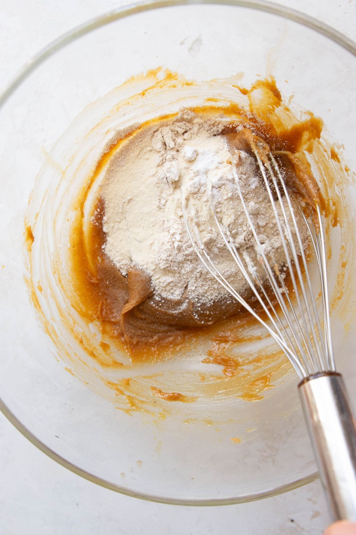 Oat flour, protein powder, baking soda, and salt added to the wet ingredients in a mixing bowl.
