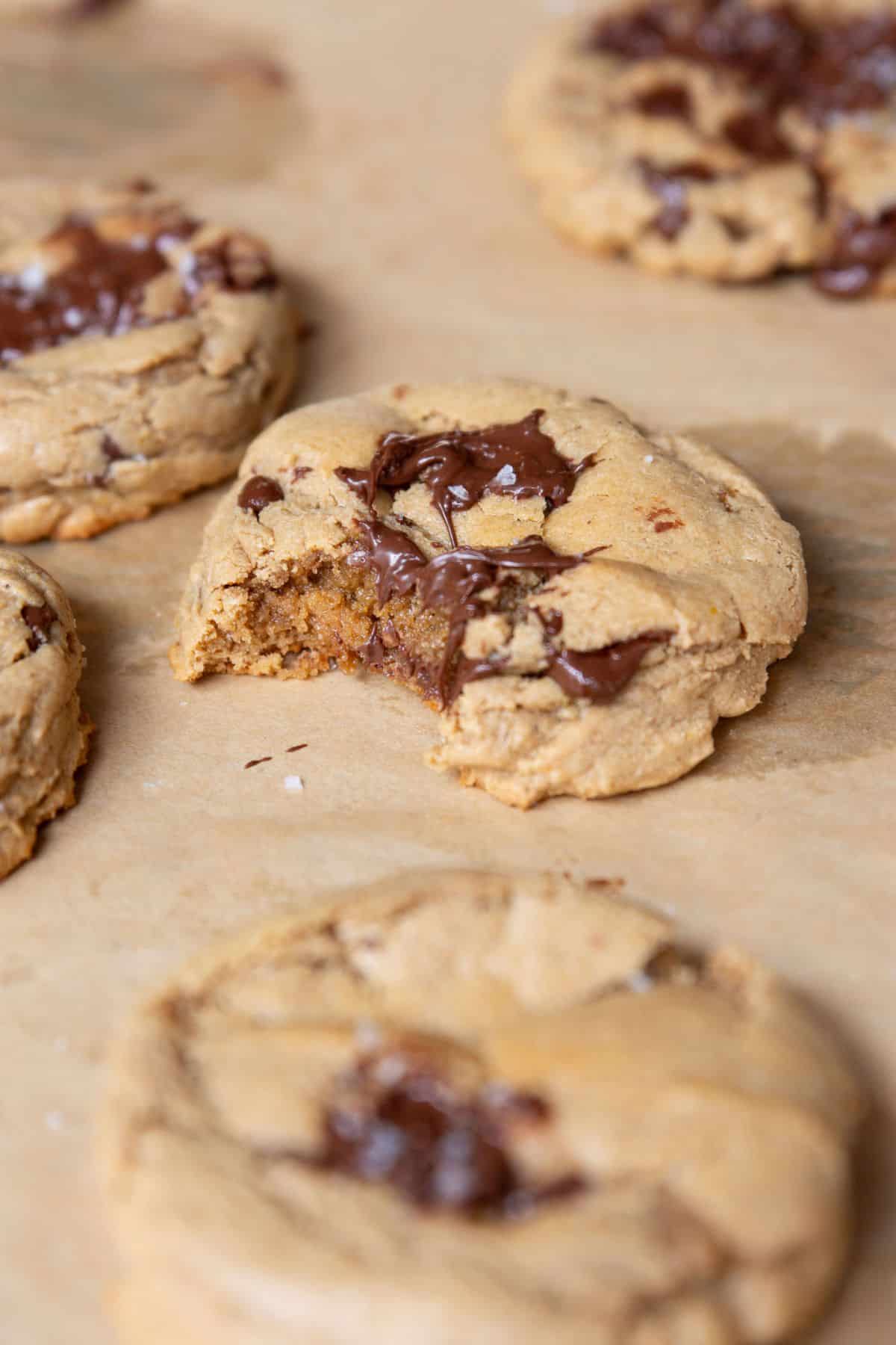 Protein chocolate chip cookie with a bite taken out showing the soft, gooey, chewy texture inside.