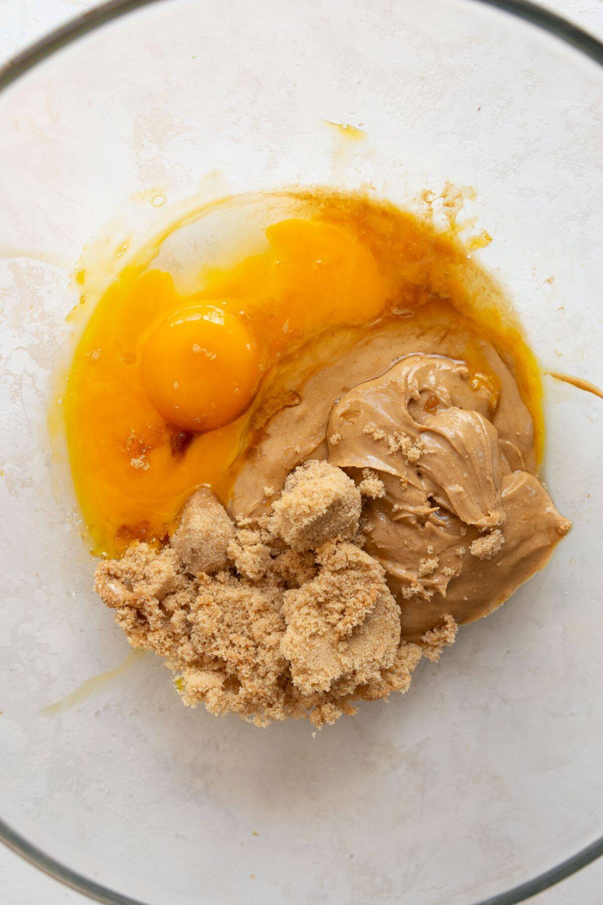 Peanut butter, brown sugar, eggs, egg yolk, and melted coconut oil whisked together in a large bowl.