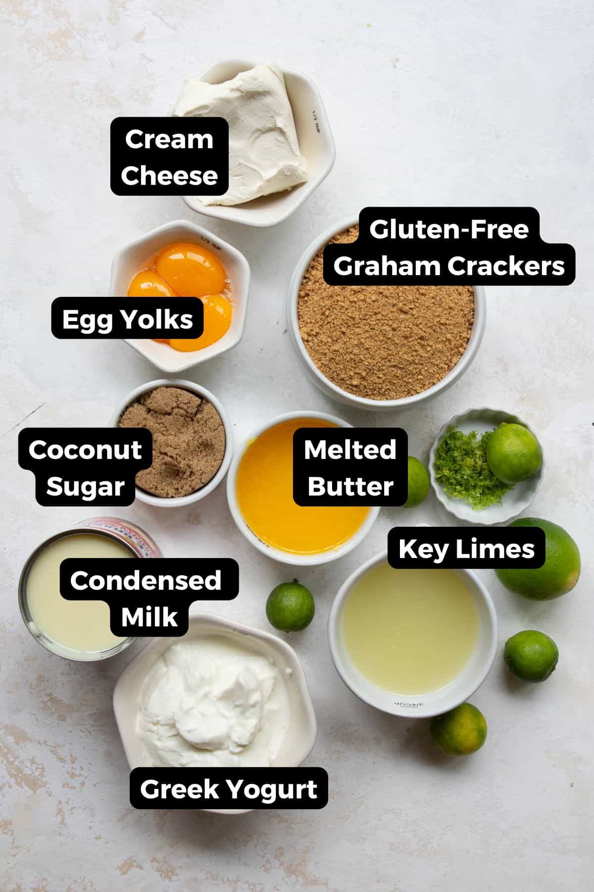 All ingredients in gluten-free key lime pie including: gluten-free graham crackers, cream cheese, greek yogurt, key limes, coconut sugar, egg yolks, melted butter, and condensed milk.
