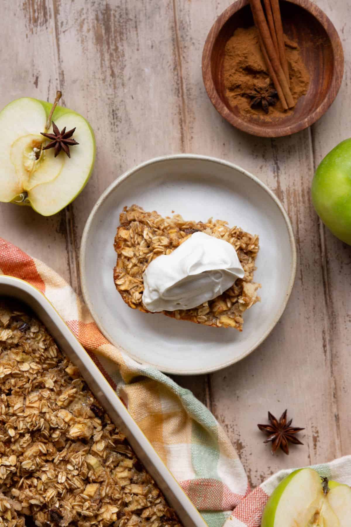 Apple cinnamon baked oatmeal served with yogurt next to the full baking dish.