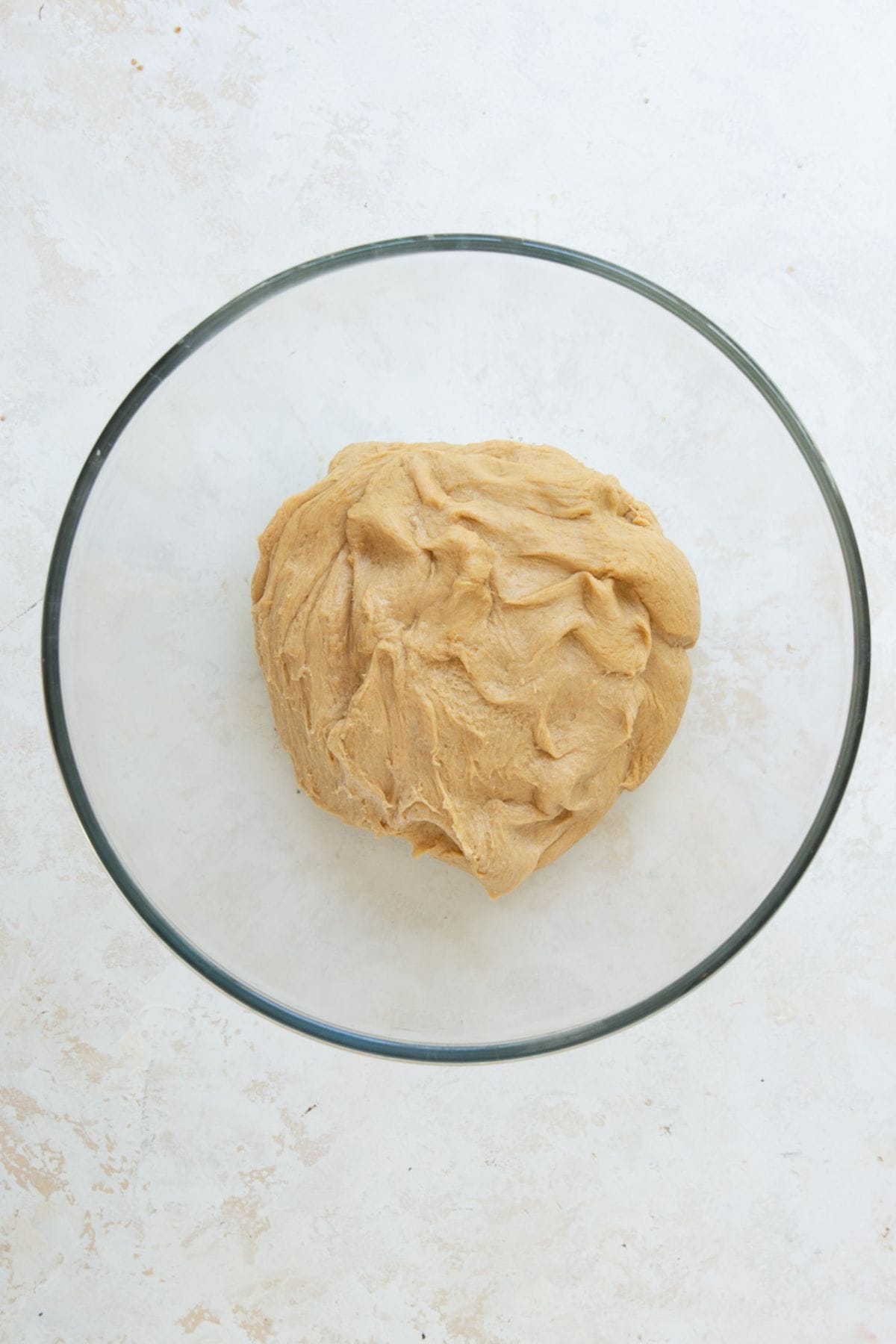 Smooth kneaded whole wheat cinnamon roll dough in a glass bowl before rising.