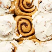 Gooey and fluffy healthy cinnamon rolls topped with Greek yogurt icing in a baking pan.