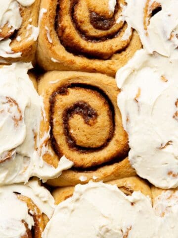 Gooey and fluffy healthy cinnamon rolls topped with Greek yogurt icing in a baking pan.