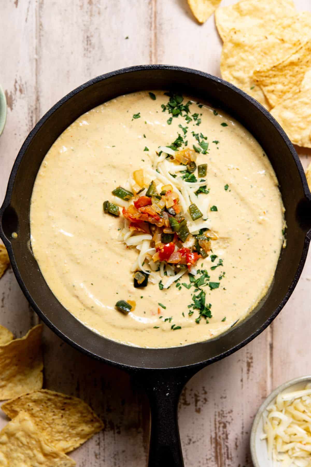 Healthy queso made with cottage cheese in a cast iron skillet with sautéed poblanos, onions, and pepper jack cheese on top.
