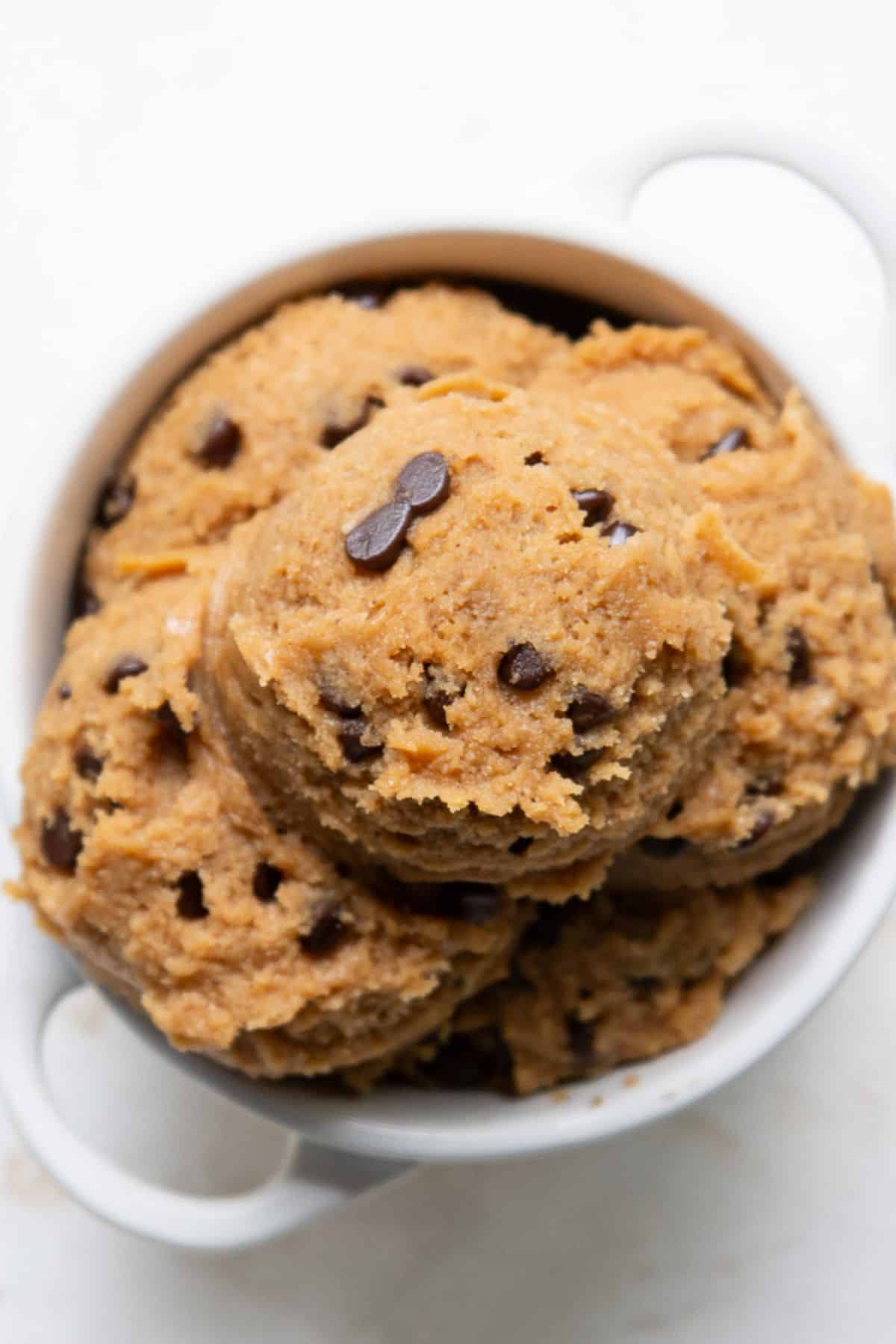 Scoops of high-protein edible cookie dough with mini chocolate chips piled in a small white bowl.