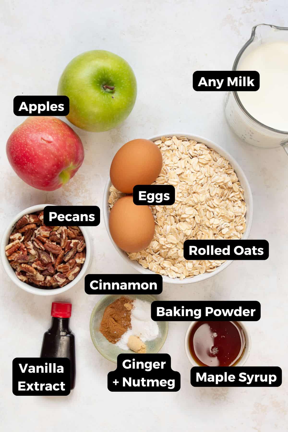 Labeled ingredients for apple cinnamon baked oatmeal including apples, oats, eggs, milk, pecans, maple syrup, and spices.