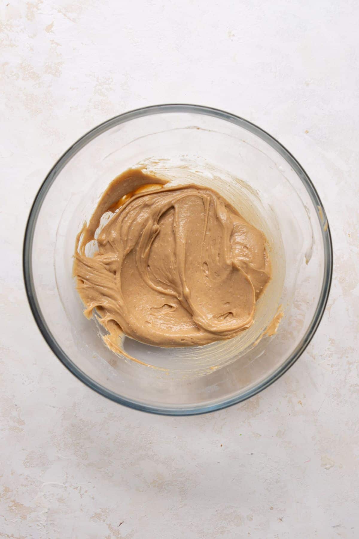 Wet ingredients for protein cookie dough whisked smooth and creamy in a glass bowl.