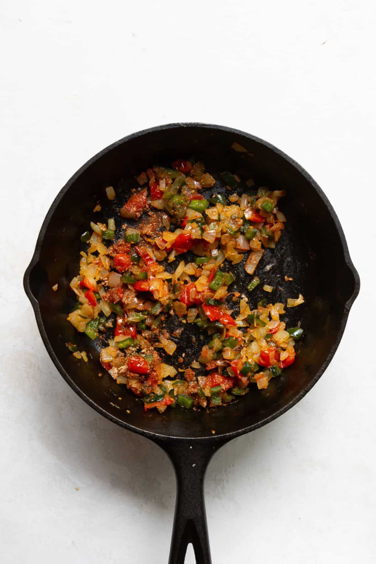 Sautéed, cooked-down vegetables with smoked paprika, cumin, and taco spices in a skillet.
