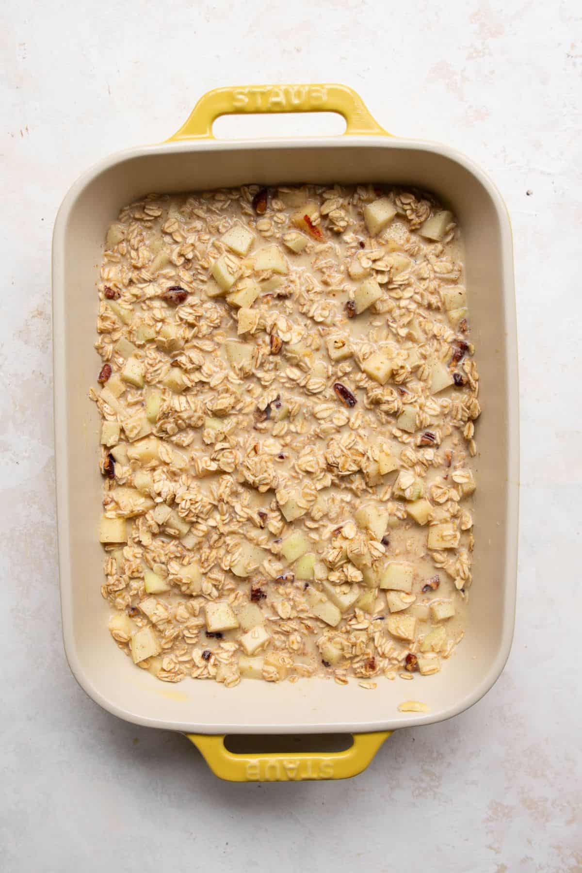 Unbaked apple cinnamon baked oatmeal pressed into a baking dish before baking.