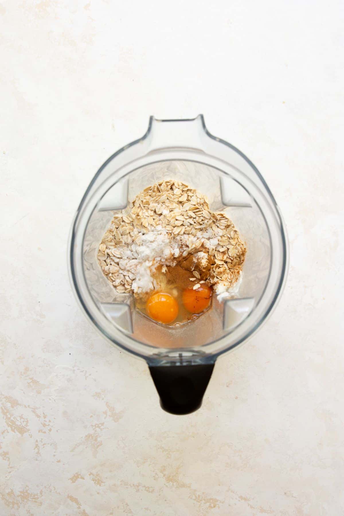 Rolled oats, eggs, cinnamon, and baking powder in a blender before making protein oatmeal pancakes.