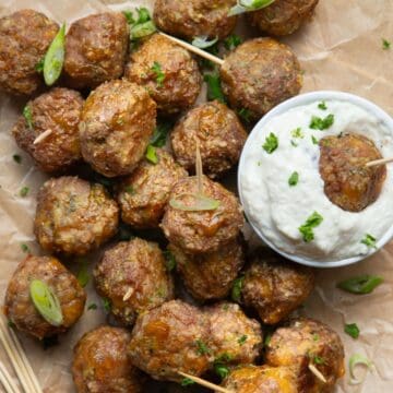 Healthy broccoli cheddar turkey meatball poppers with Greek yogurt ranch dip, garnished with scallions.