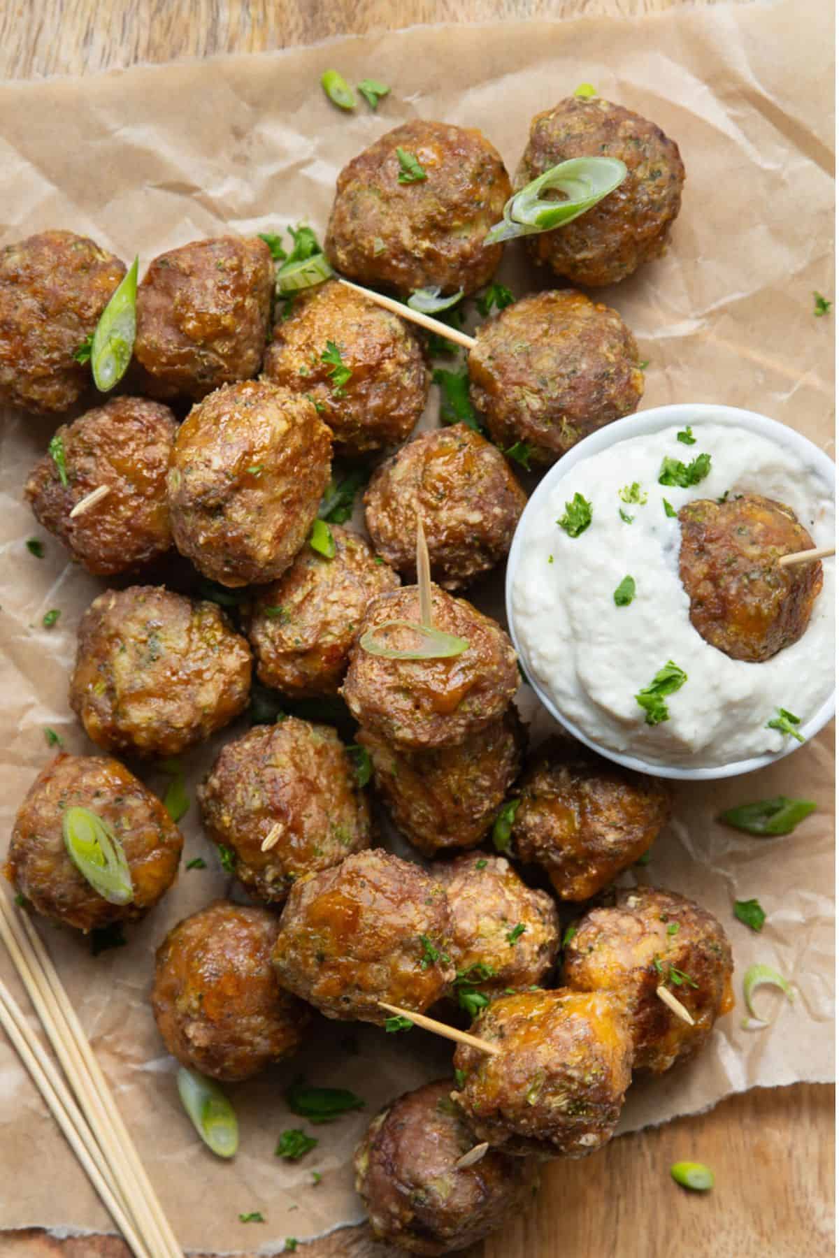 Overhead view of healthy broccoli cheddar turkey meatballs on toothpicks served with a bowl of creamy ranch dip.