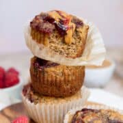 Healthy peanut butter and jelly banana muffins stacked with peanut butter and raspberry jam swirled over the top.