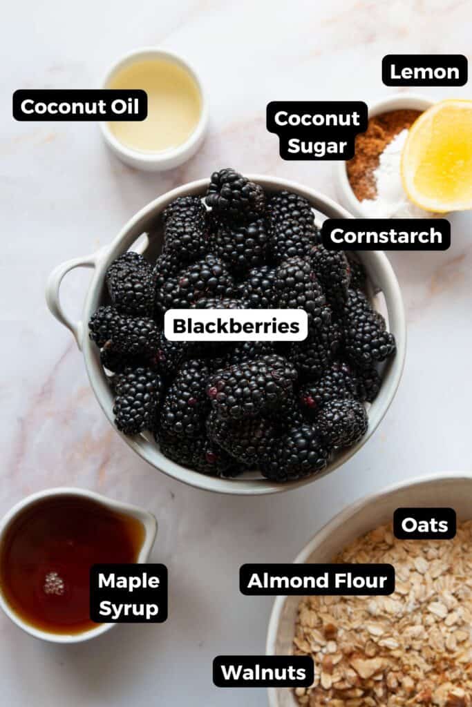 Ingredients for blackberry crumble including fresh blackberries, rolled oats, maple syrup, and lemon.