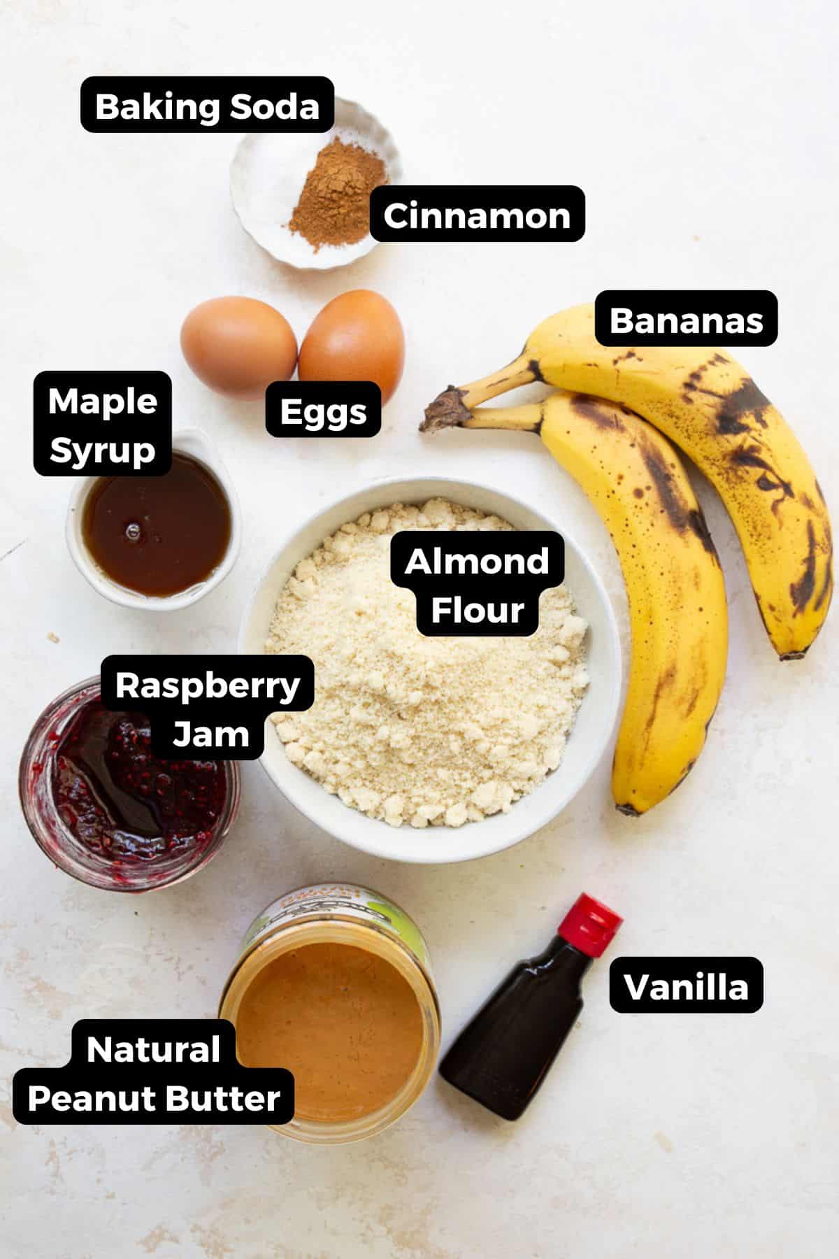 Ingredients for healthy peanut butter and jelly banana muffins including almond flour, ripe bananas, peanut butter, eggs, maple syrup, raspberry jam, cinnamon, baking soda and vanilla.