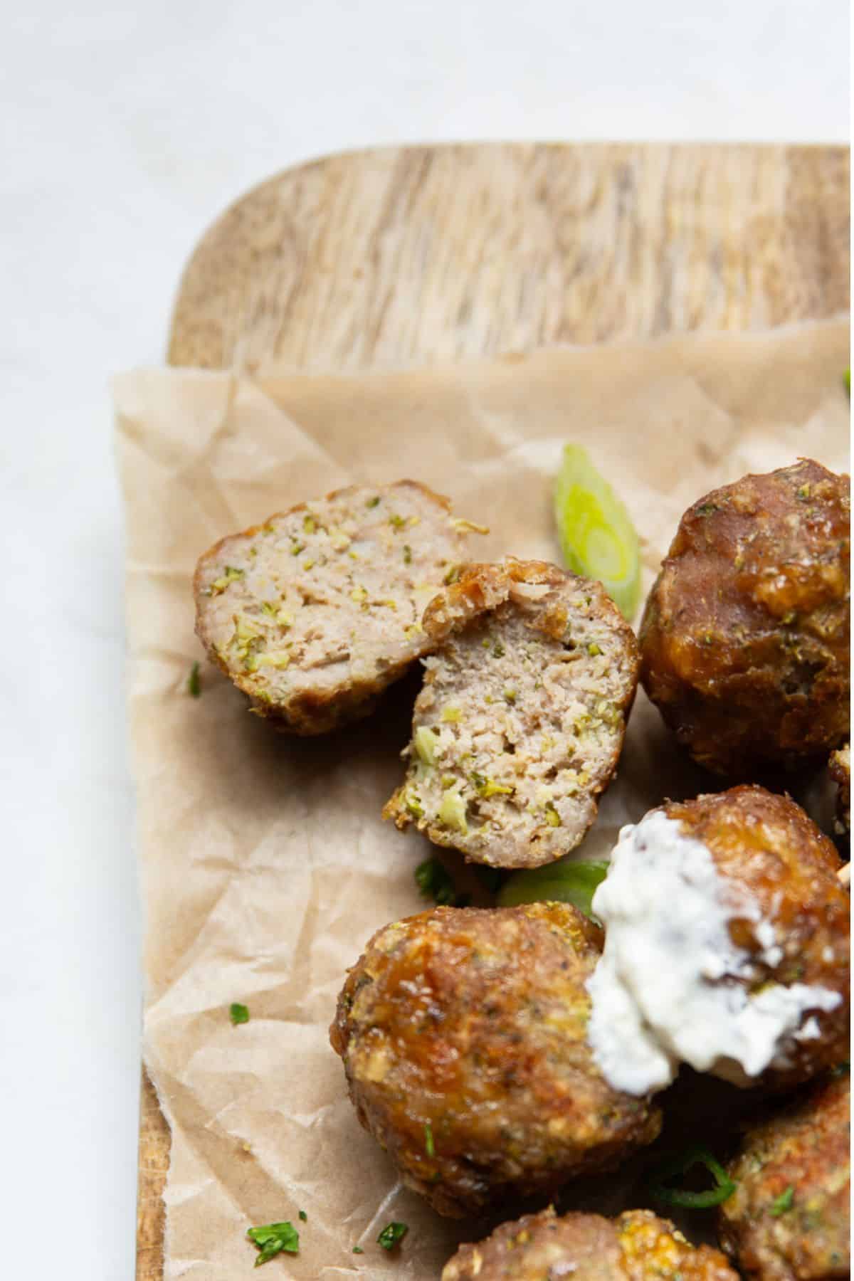Inside of a broccoli cheddar turkey meatball cut open, showing the moist texture and flecks of hidden broccoli.