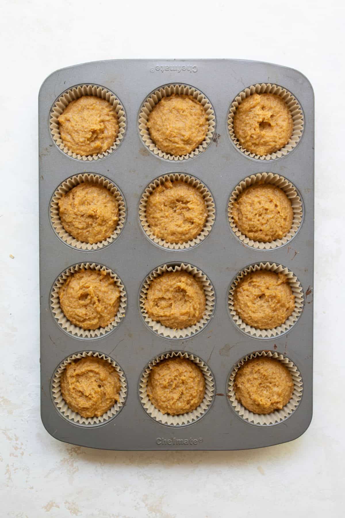 Peanut butter banana muffin batter scooped into a 12-cup lined muffin tin.