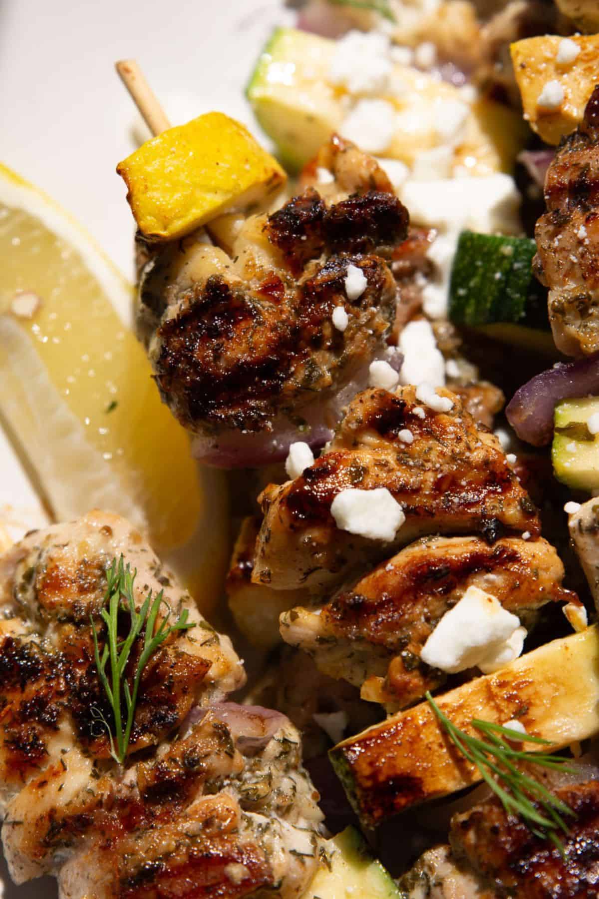 Tender grilled Greek chicken kabobs with zucchini, squash, and crumbled feta.