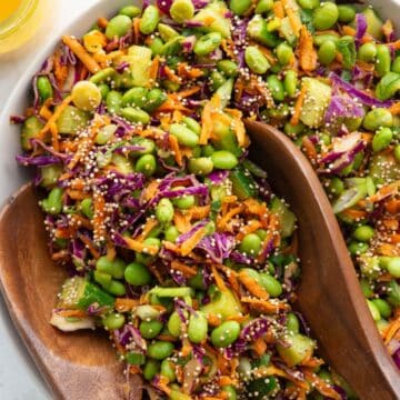 Easy Asian edamame crunch salad with puffed quinoa, cucumber, carrots, and cabbage, dressed in carrot ginger dressing.