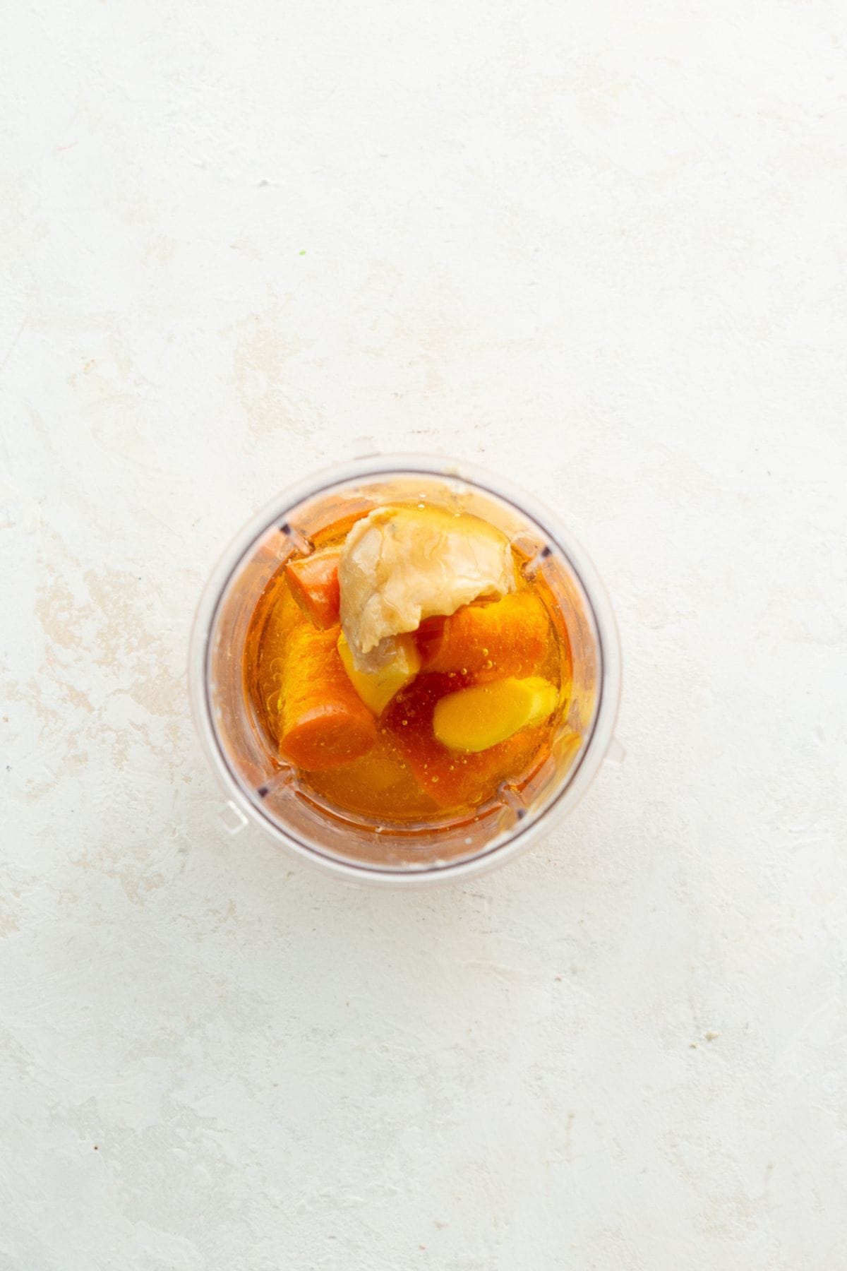 Carrot, fresh ginger, miso, and honey in a blender before blending into carrot ginger dressing.