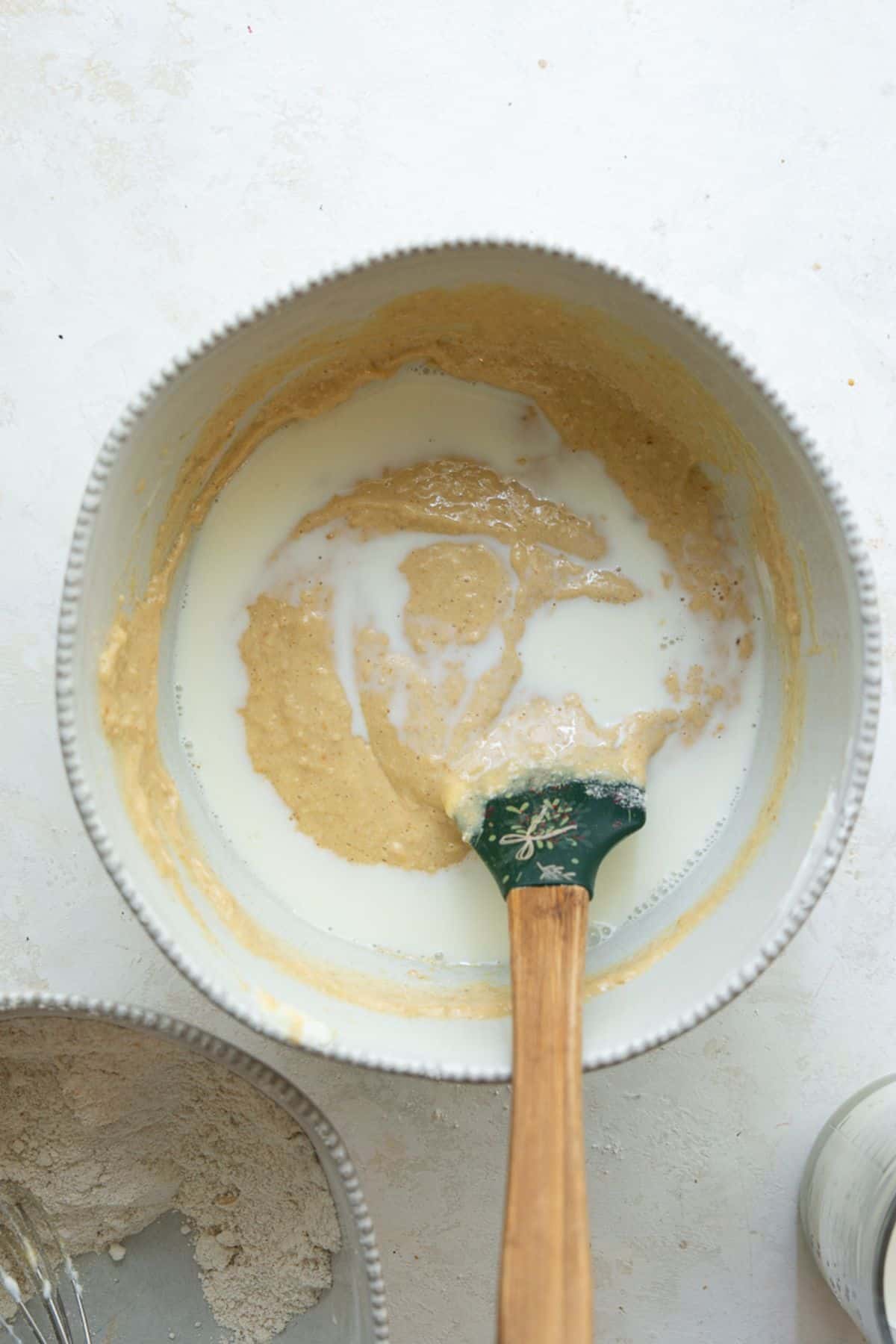 Folding milk and oat flour into protein cake batter with a spatula.
