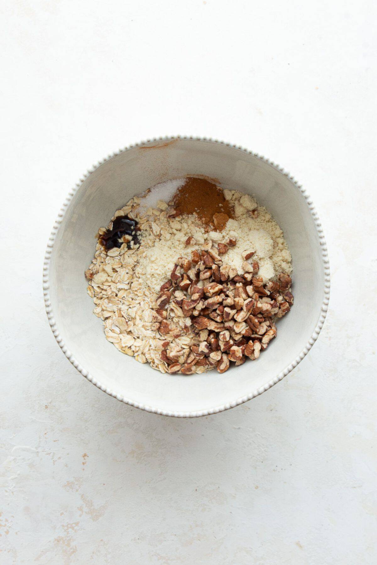 Rolled oats, almond flour, pecans, cinnamon, and vanilla in a bowl for the crumble topping.