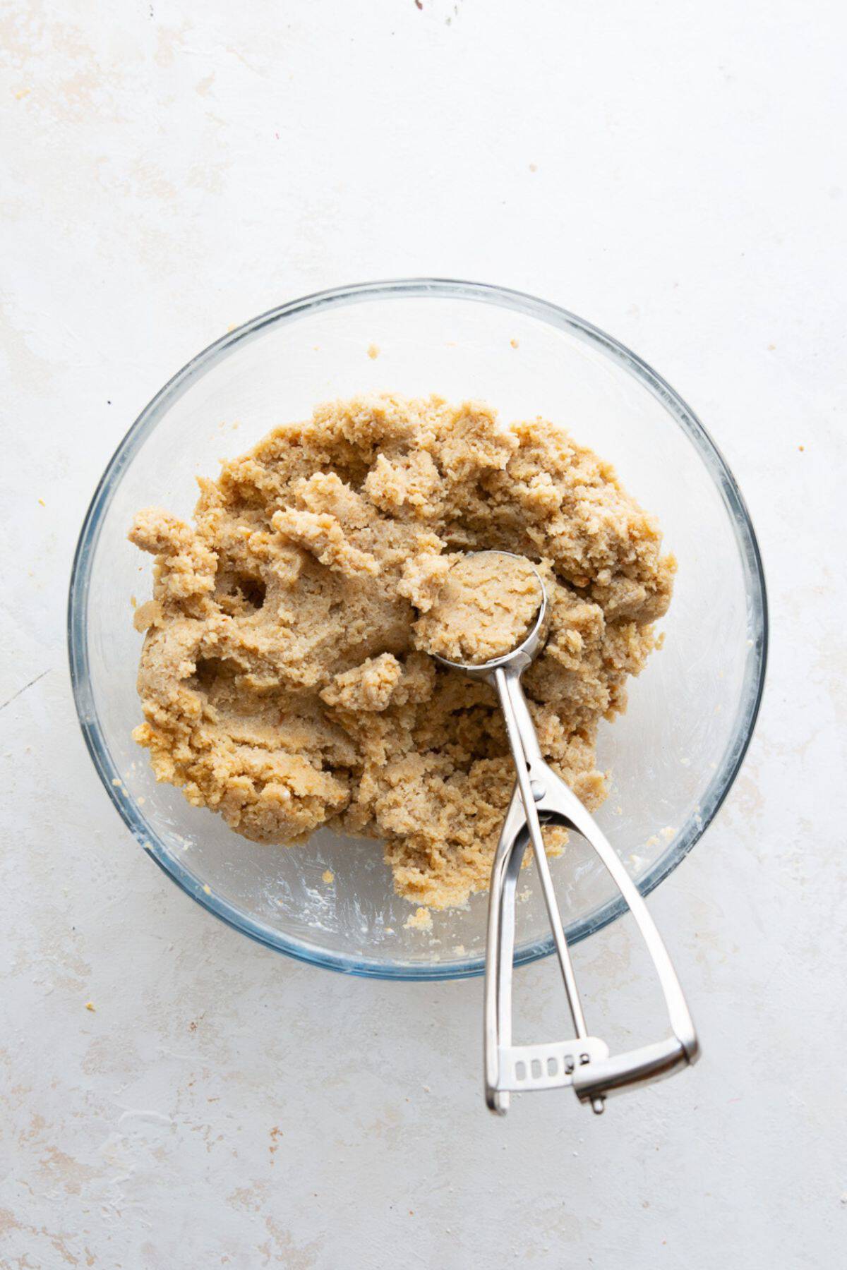 Protein cake pop filling in a bowl with a cookie scoop ready to portion.