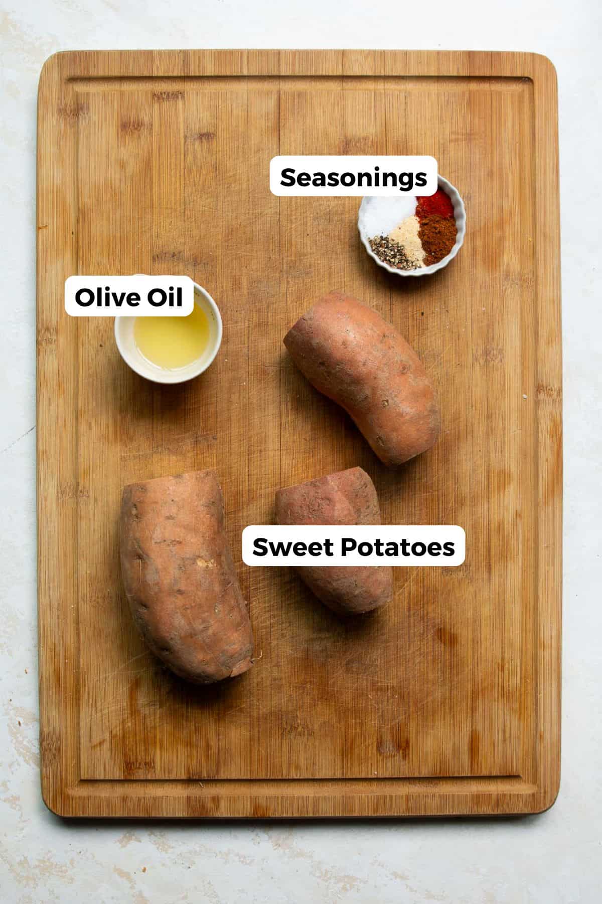 Sweet potato cubes in a bowl with olive oil, salt, pepper, paprika, and garlic powder.