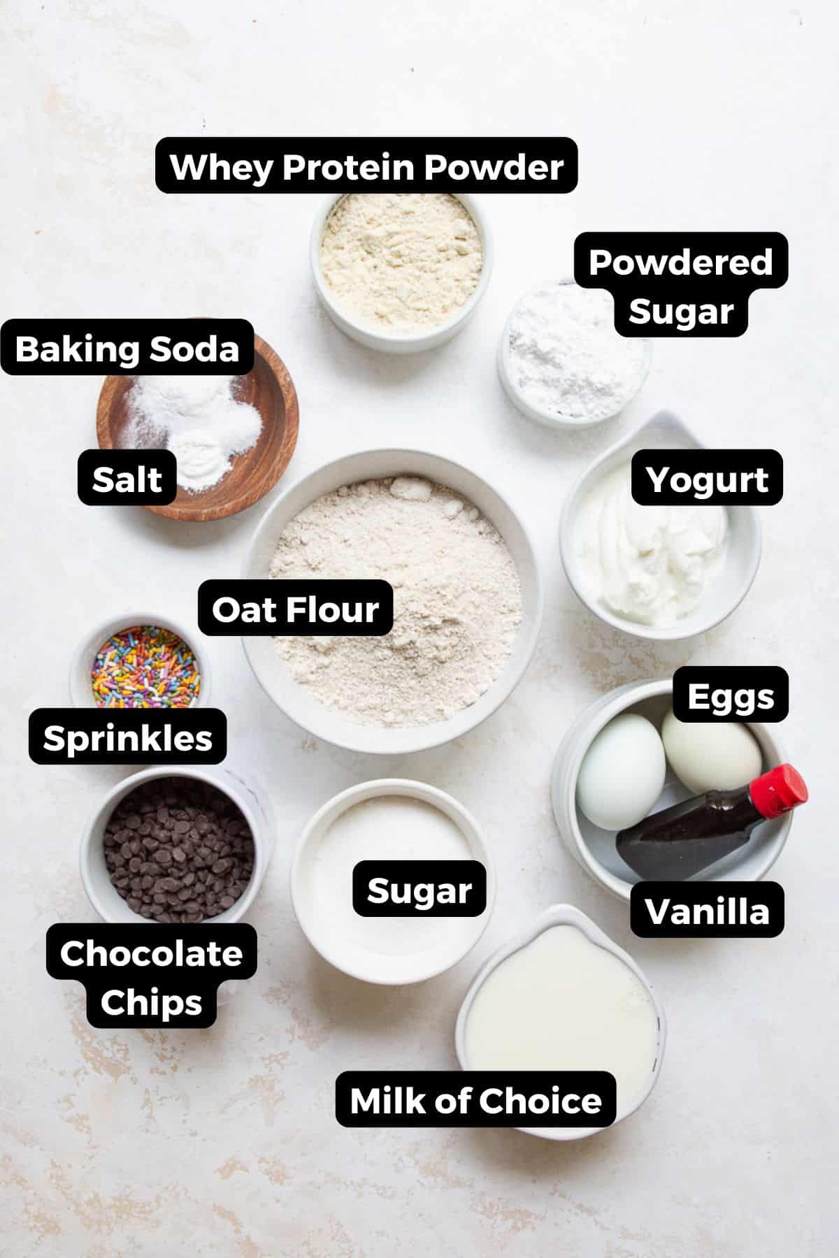 Labeled ingredients for healthy protein cake pops, including whey protein powder, oat flour, Greek yogurt, eggs, sugar, and chocolate chips.