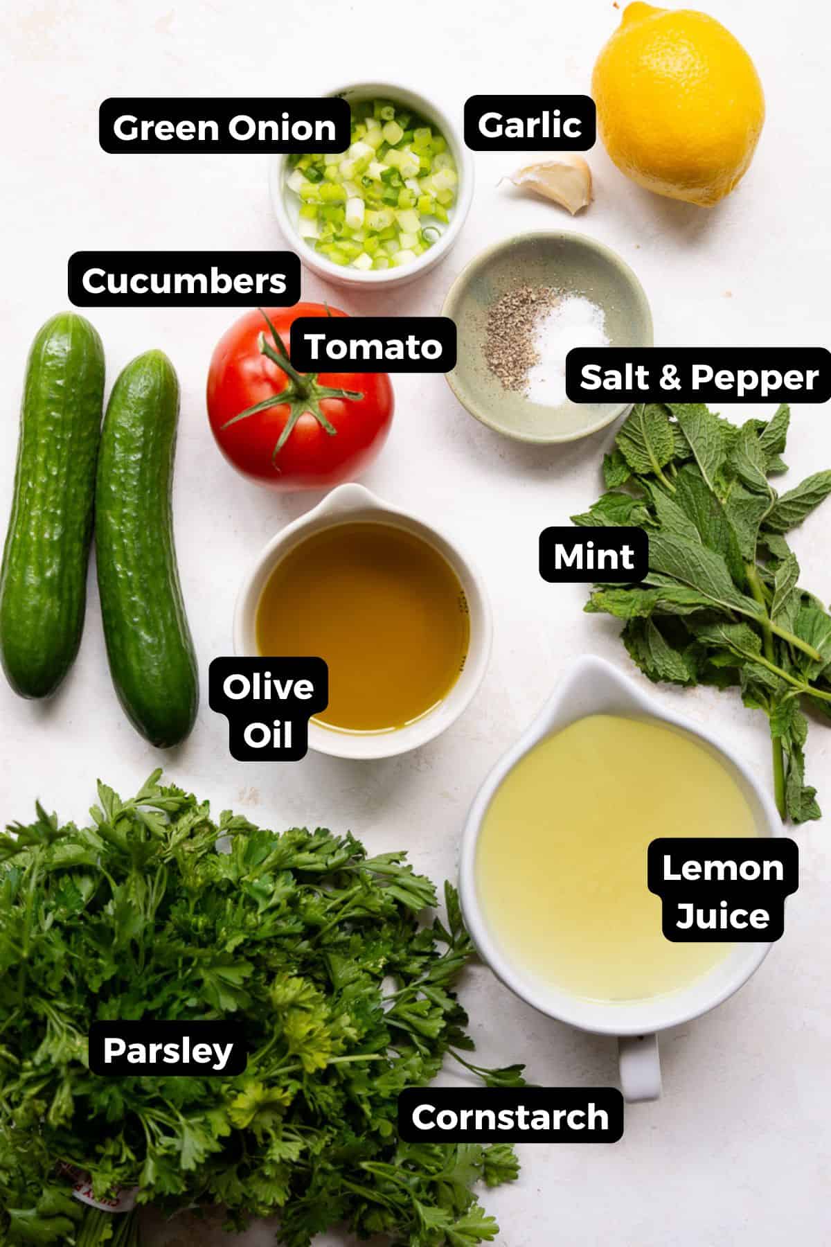 Ingredients for Mediterranean quinoa tabbouleh salad including parsley, mint, cucumber, tomato, scallions, garlic, lemon, and olive oil.