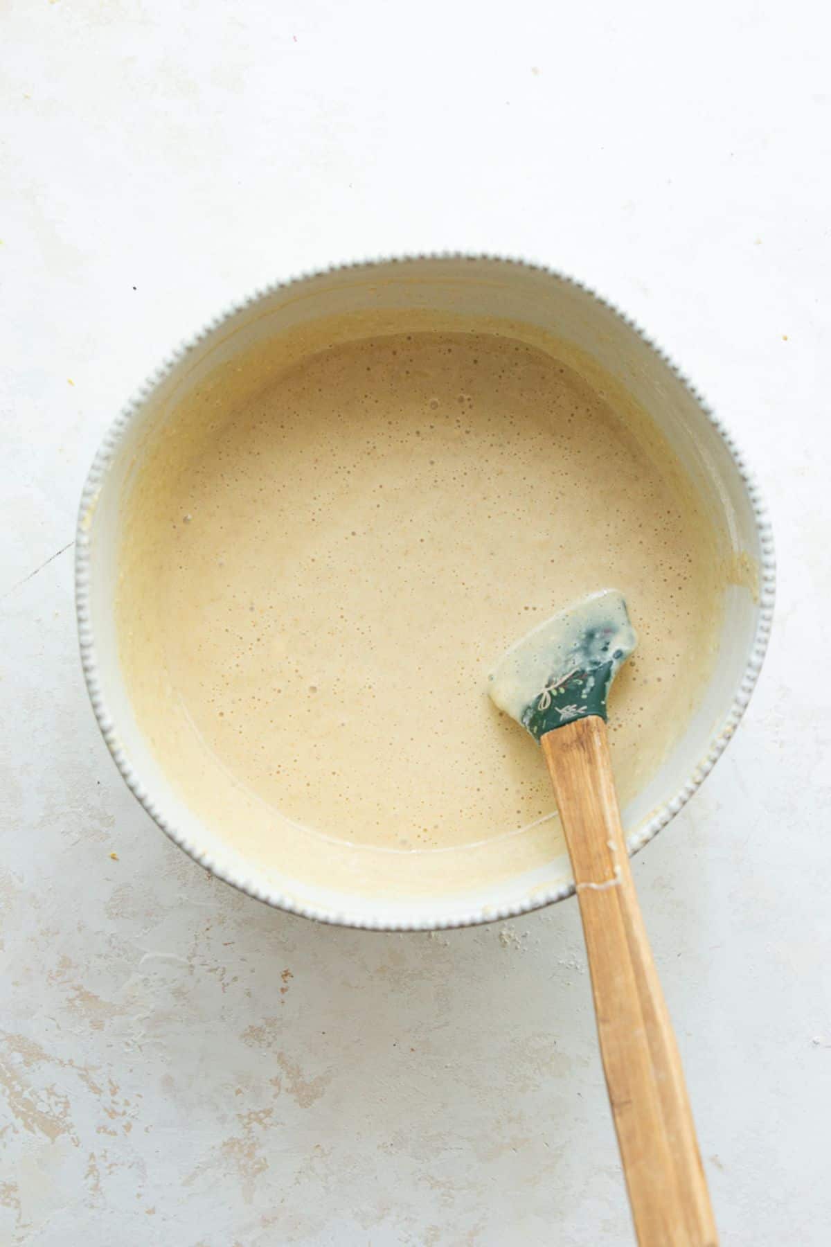 Smooth vanilla protein cake batter in a white mixing bowl before baking.
