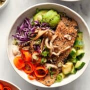 Baked furikake salmon fillet over white rice with shiitake mushrooms, avocado, cucumber, purple cabbage, and carrot ribbons.