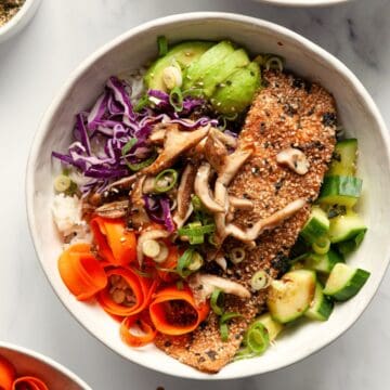 Baked furikake salmon fillet over white rice with shiitake mushrooms, avocado, cucumber, purple cabbage, and carrot ribbons.