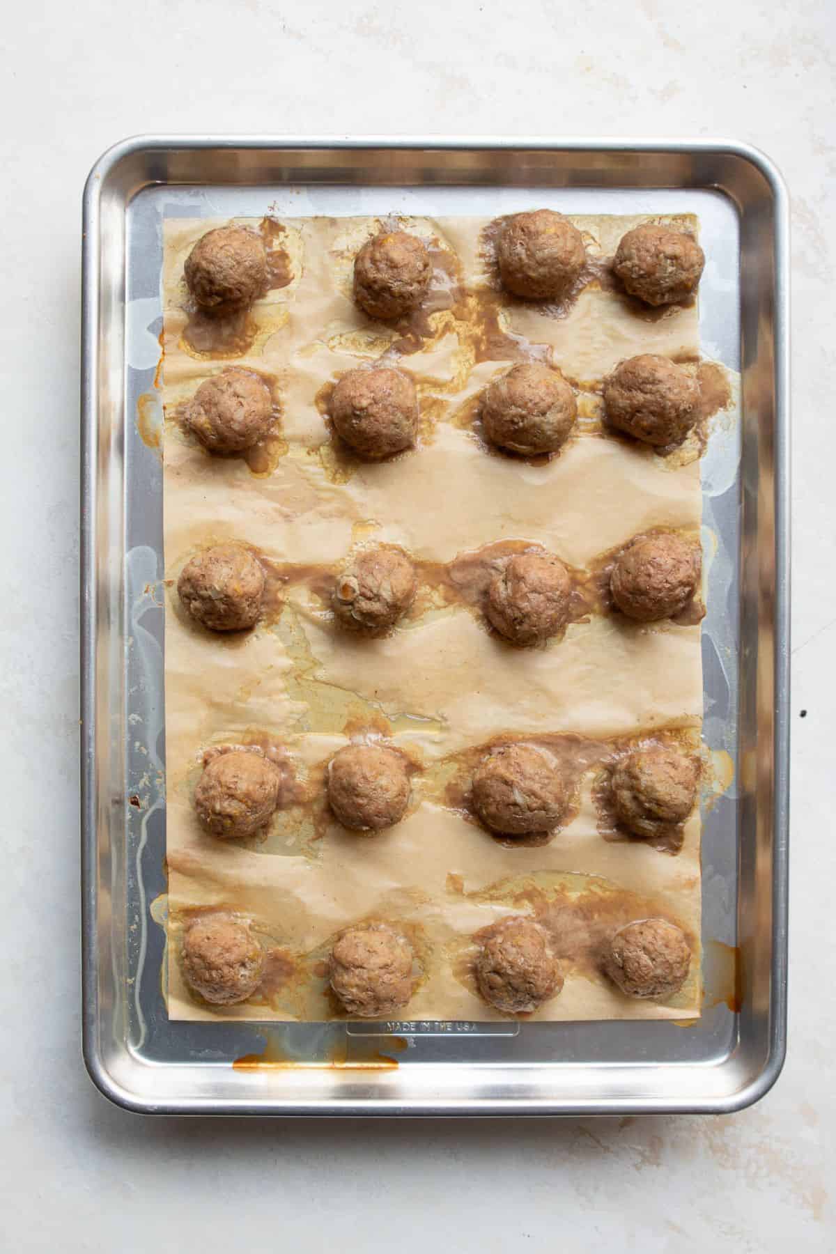 Baked Greek turkey meatballs on a sheet pan after 15 minutes in the oven.