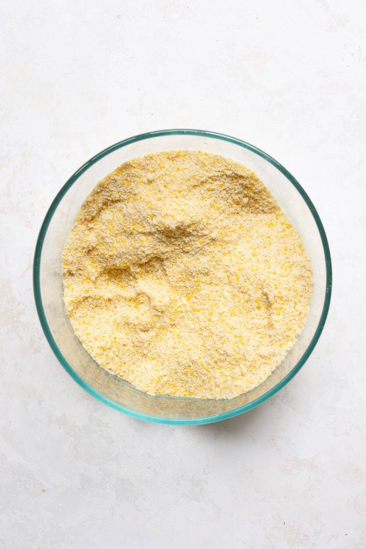 Cornmeal and almond flour whisked together in a glass bowl.