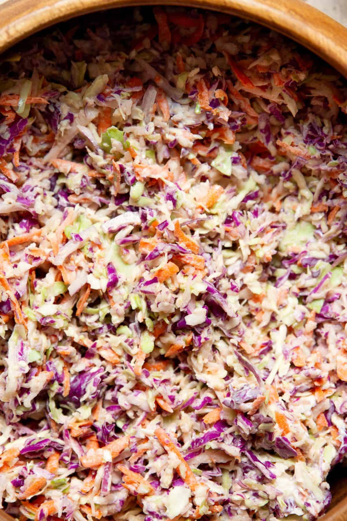 Close up of creamy healthy coleslaw made with Greek yogurt in a wooden serving bowl.