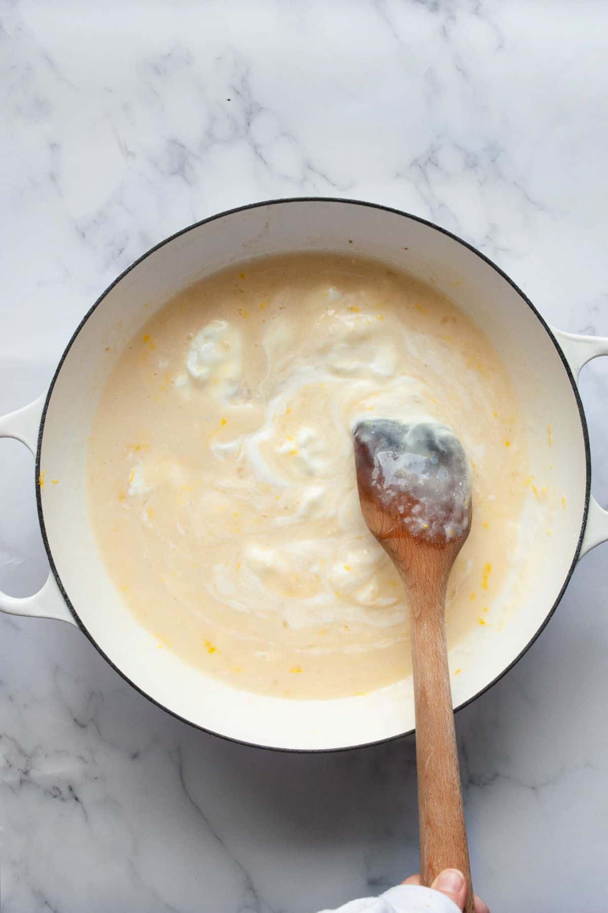 Adding yogurt to cream sauce off the heat.