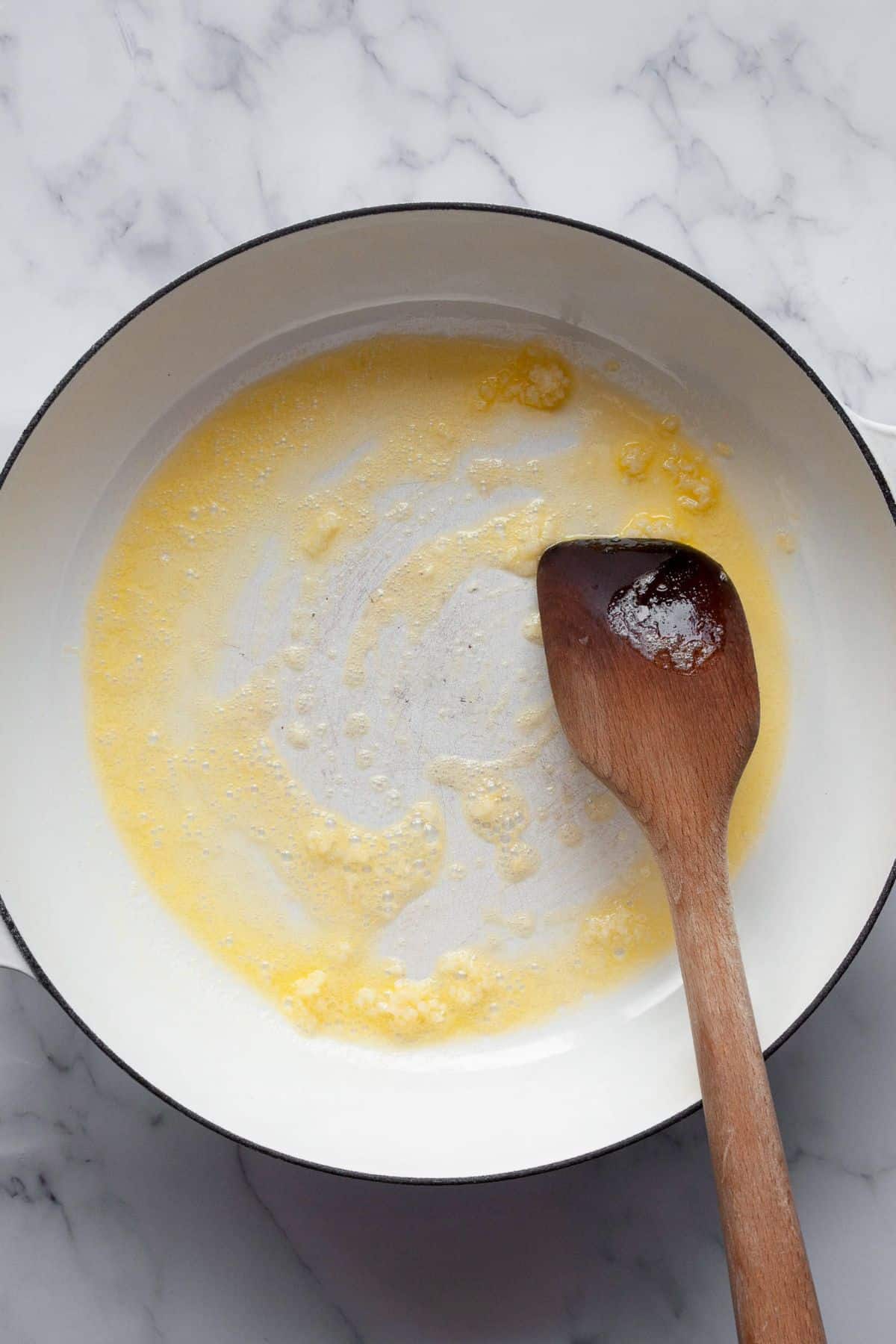 Melted butter and minced garlic in a white pan.