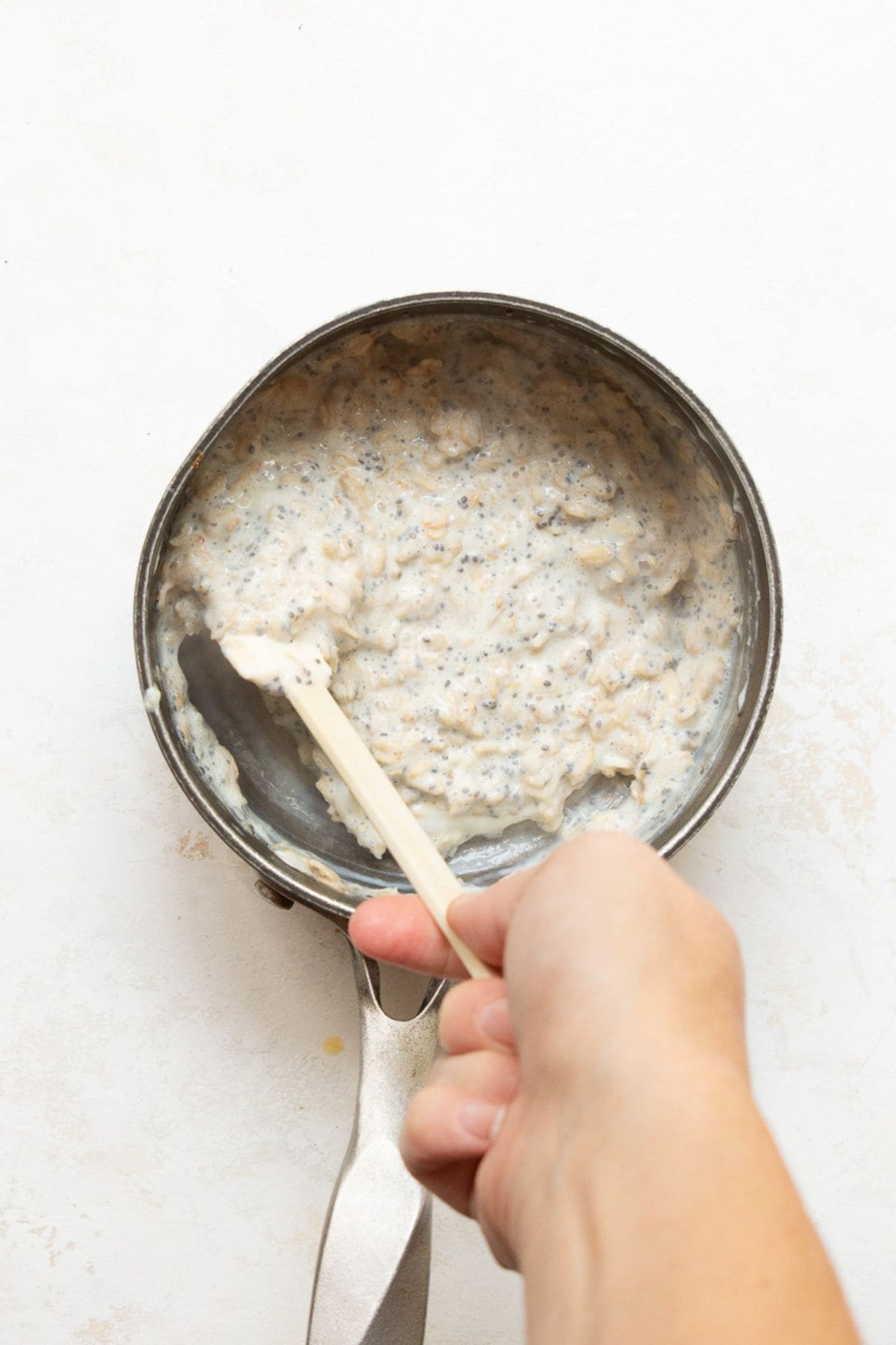 Stirring egg whites and chia seeds into cooked oatmeal off the heat.