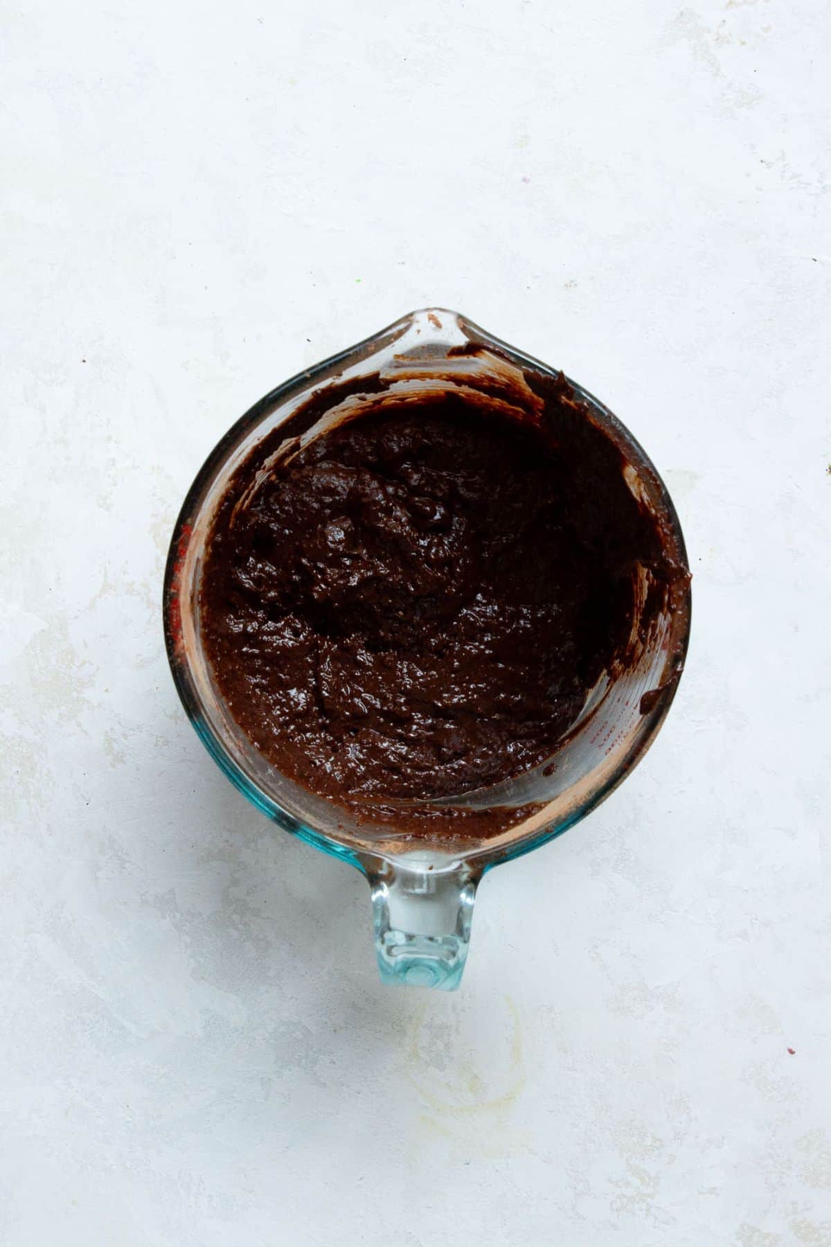 Thick flourless brownie batter in a glass bowl before going into the skillet.