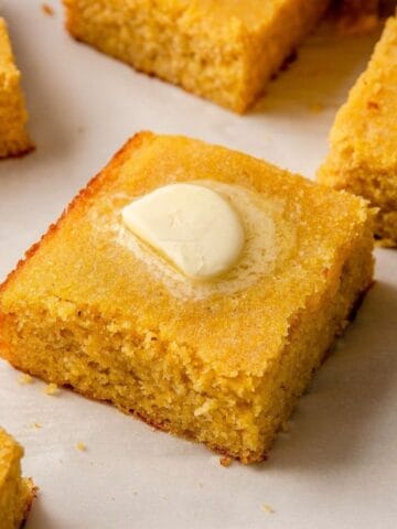 Square of healthy almond flour cornbread topped with a pat of butter.
