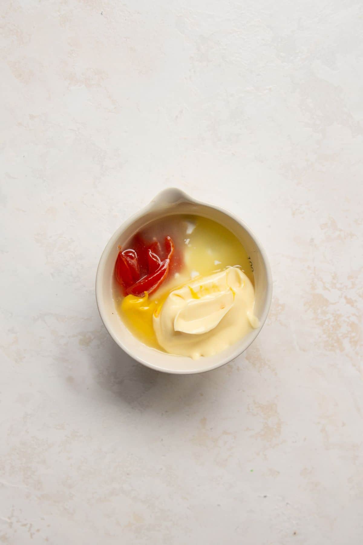 Ketchup, mustard, mayo, and pickle juice in a small bowl before whisking.