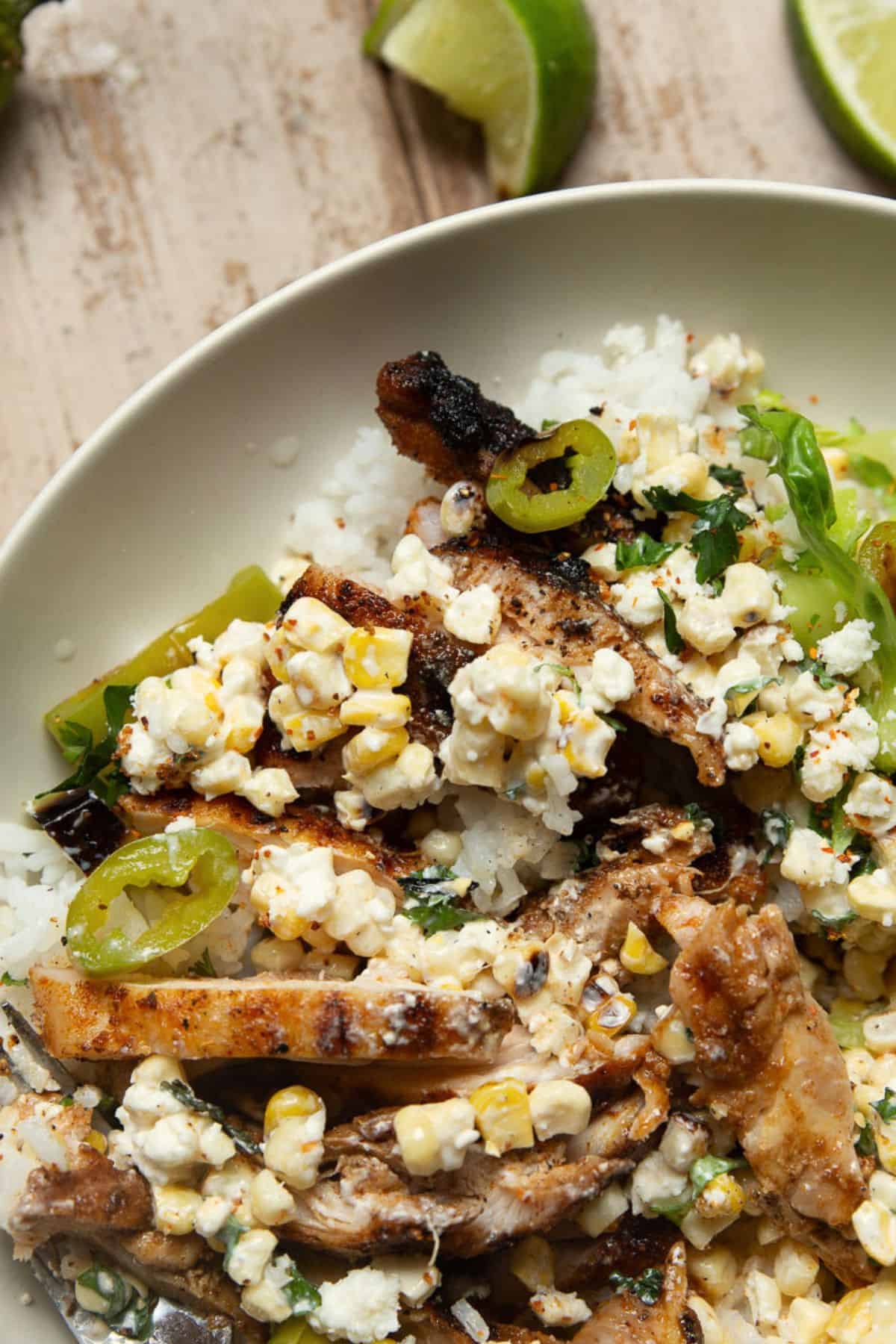 Mexican street corn chicken and rice bowl topped with cotija, cilantro, and esquites corn.