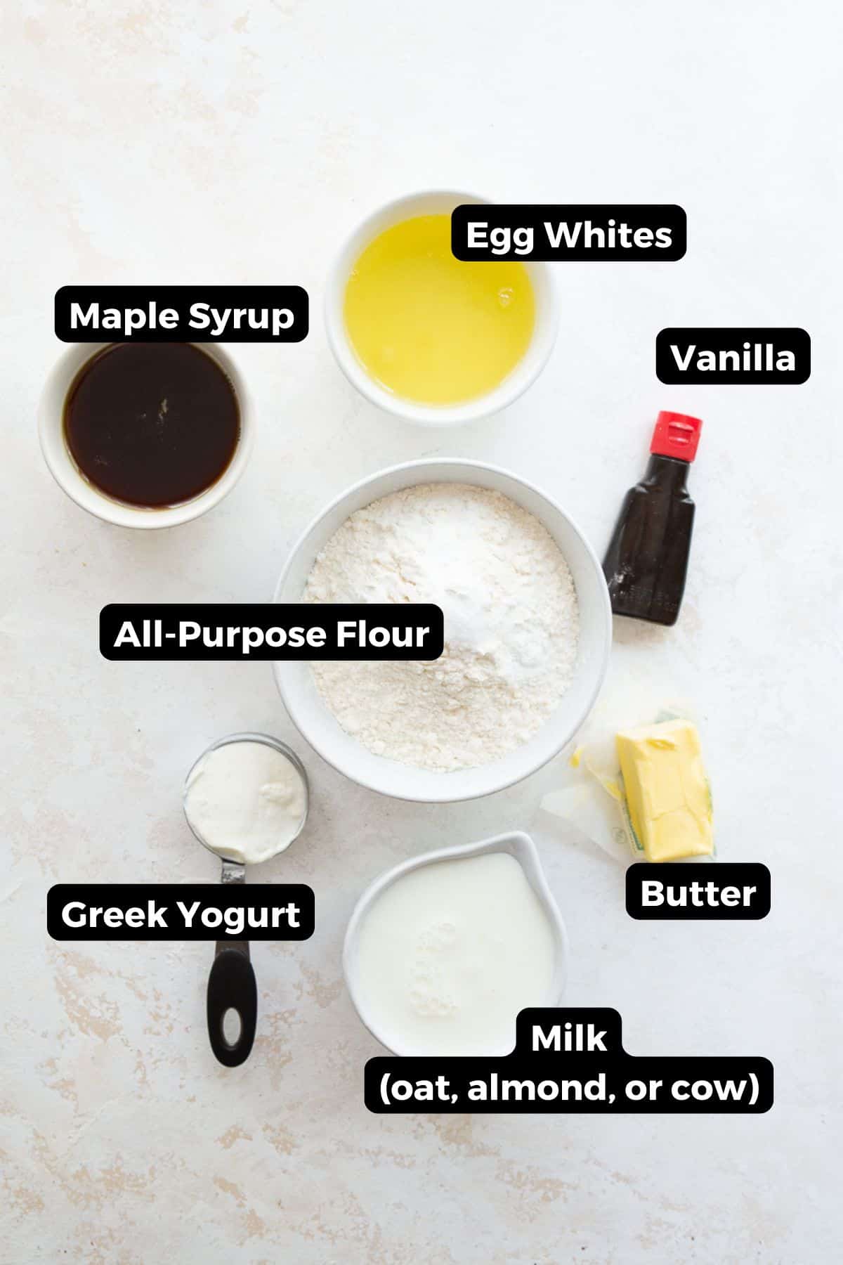 Ingredients for healthy vanilla cupcakes: maple syrup, egg whites, flour, Greek yogurt, oat milk, butter, and vanilla extract.