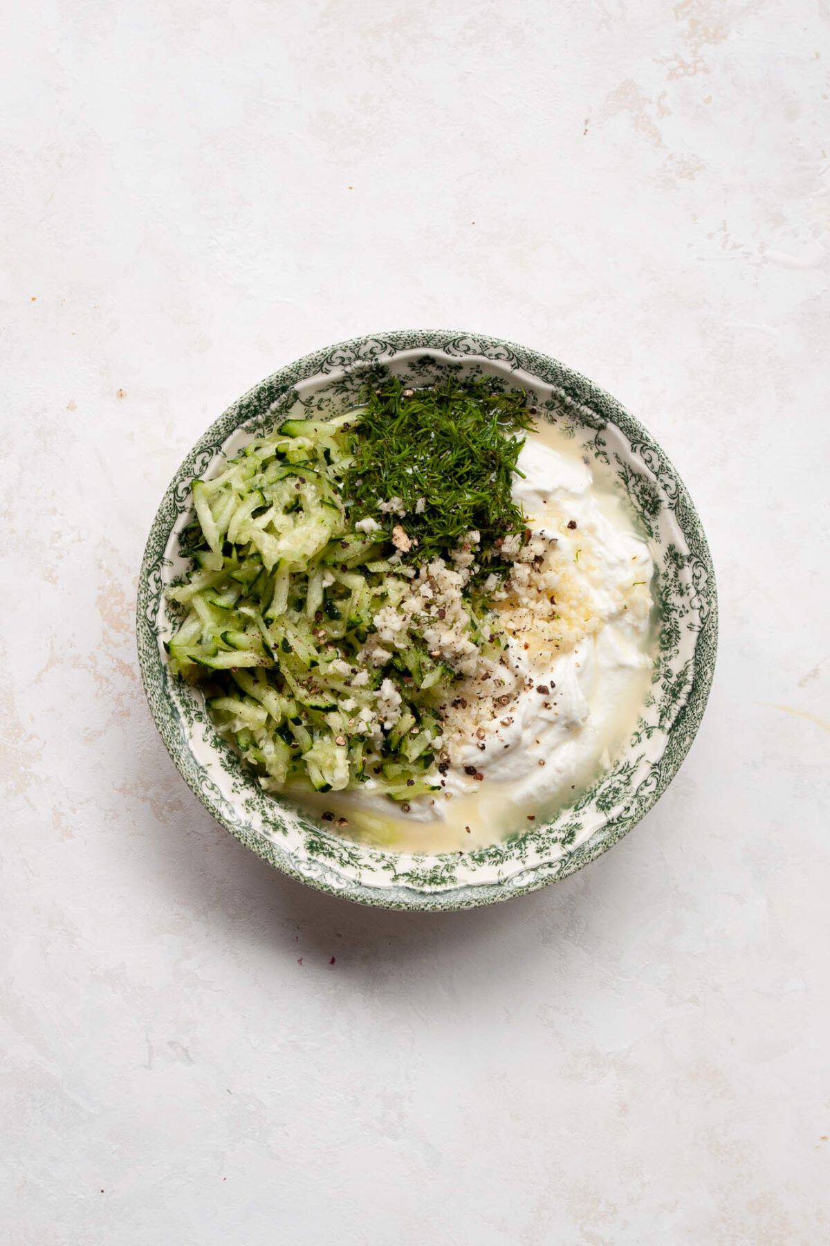 Grated cucumber, fresh dill, minced garlic, and black pepper on top of Greek yogurt to make tzatziki.