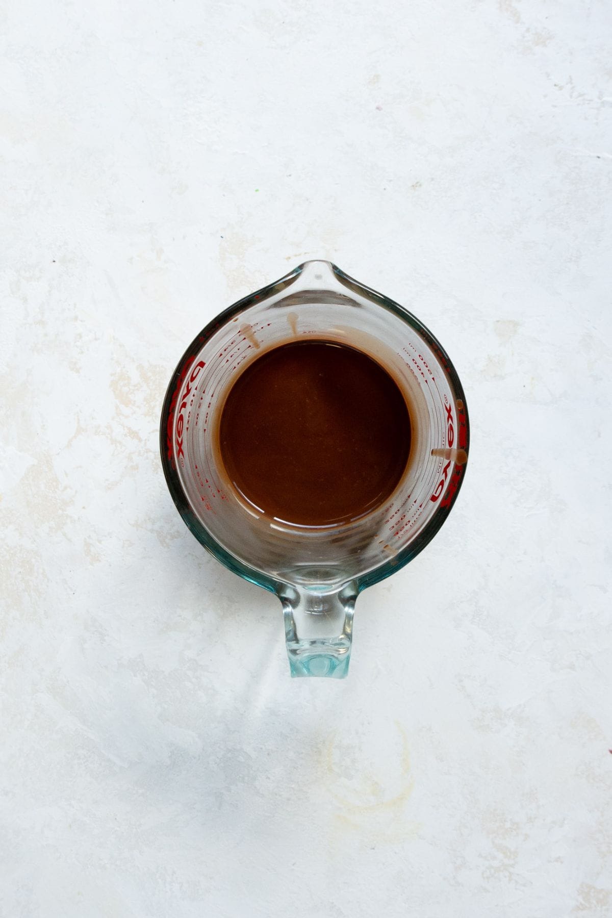 Melted dark chocolate and coconut oil in a glass measuring cup.