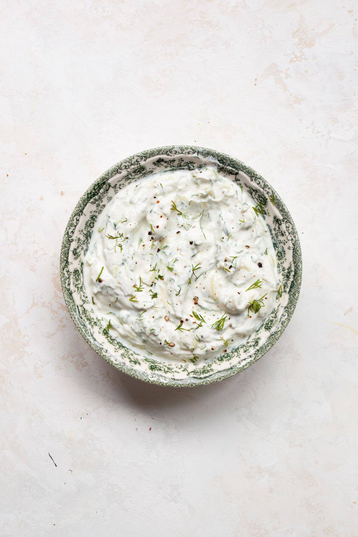 Finished tzatziki sauce stirred together in a bowl.