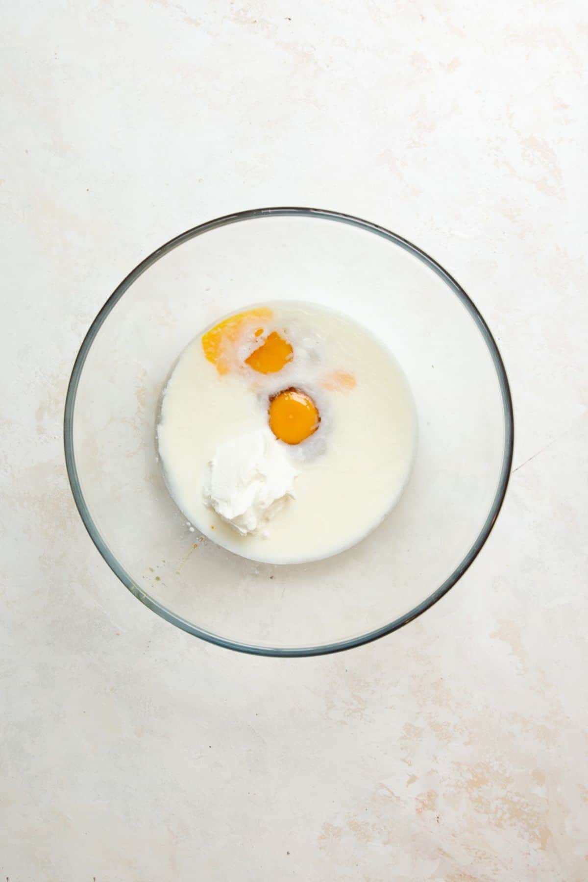 Eggs, Greek yogurt, milk, and honey in a glass mixing bowl before whisking.