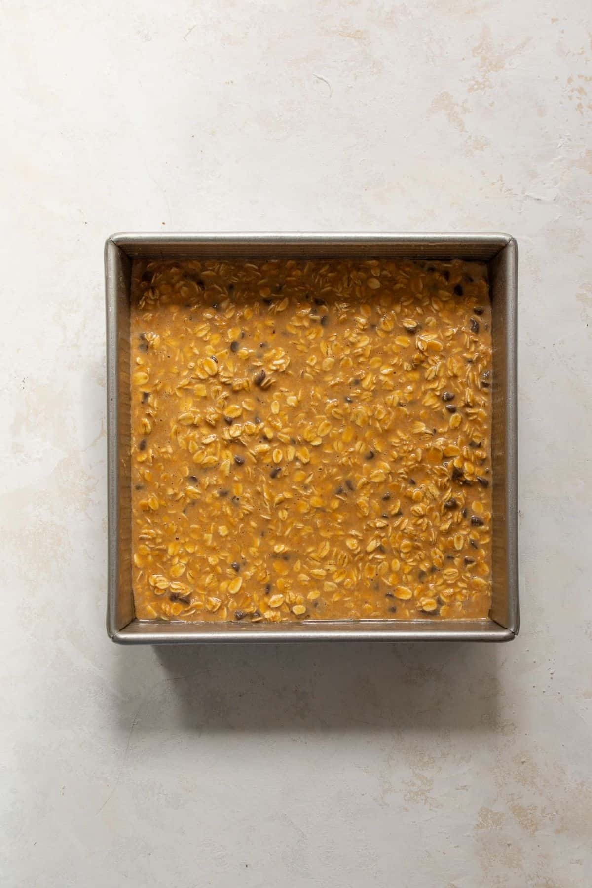 Pumpkin baked oatmeal batter spread in a square baking dish before baking.